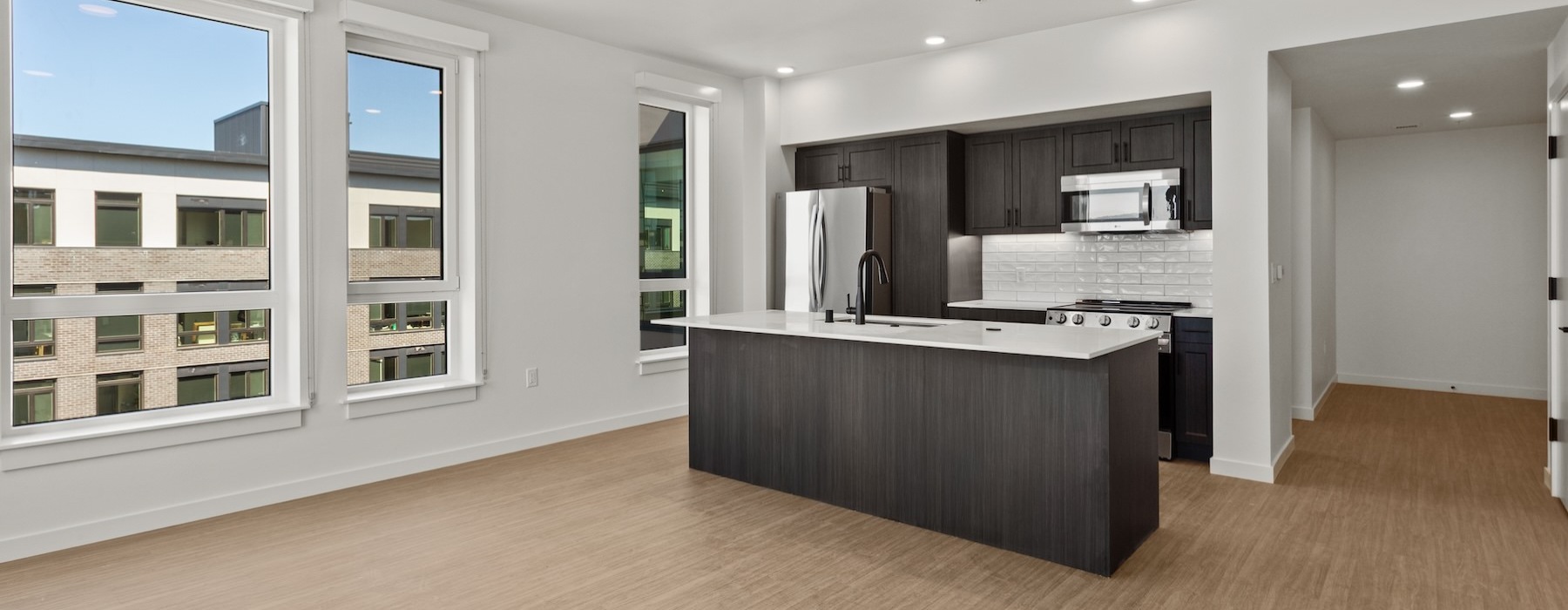 a kitchen with wood floors and large windows
